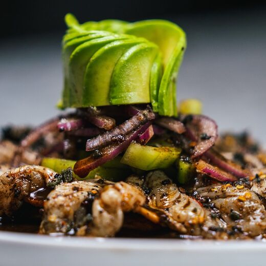 An avocado rose over dark-sauced oysters and scallops